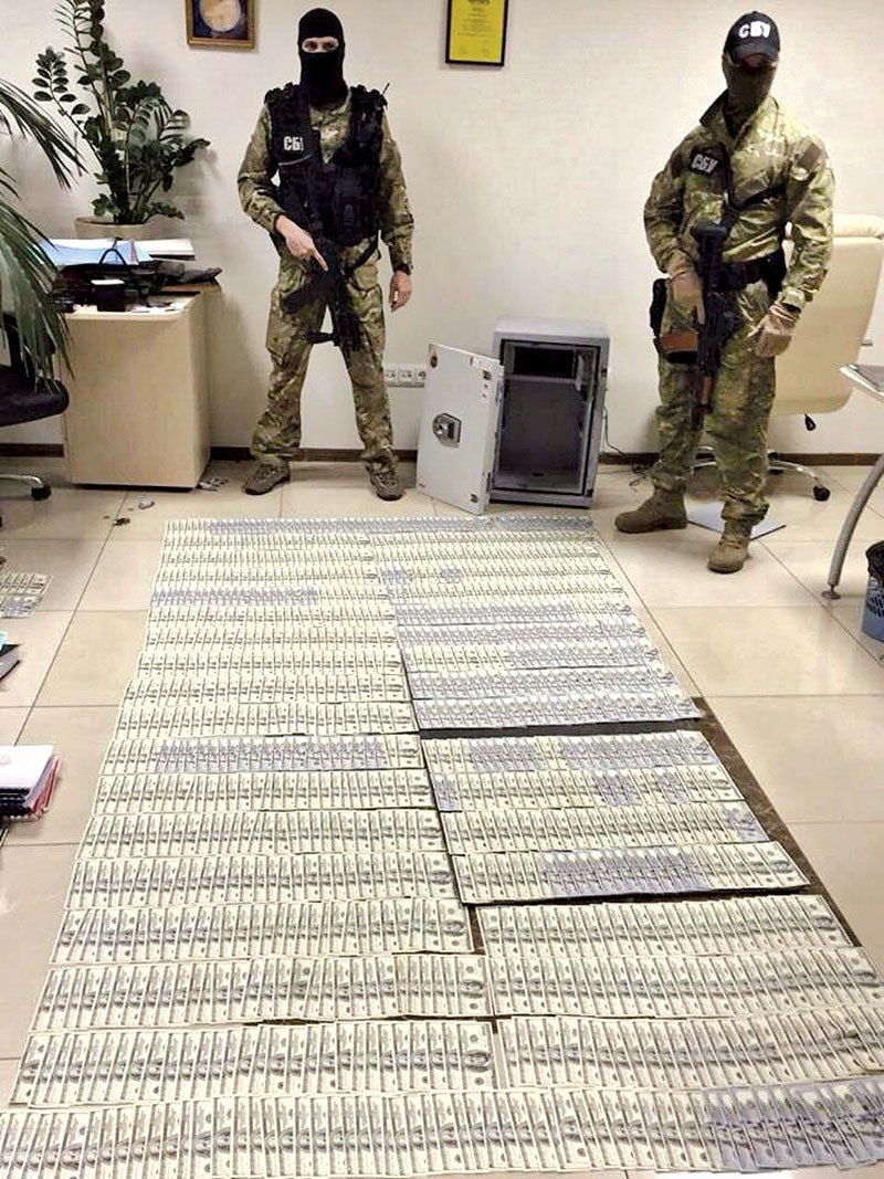 Armed security service officers guard cash found during a search of the main investigative branch of the General Prosecutor’s Office on July 5. (UNIAN)