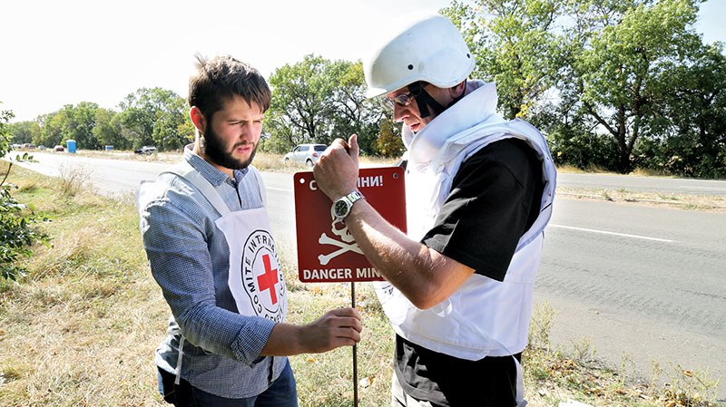 nternational Committee of the Red Cross staff members install a land mine warning sign in the village of Berezove in Donetsk Oblast on Sept. 26.