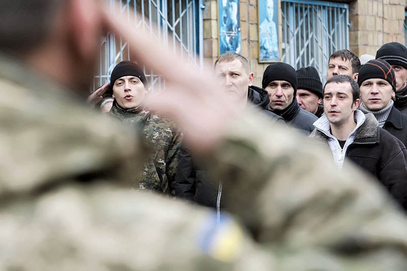 Men sing the Ukrainian national anthem at the Desnyansky recruitment office on Jan. 29 in Kyiv as they prepare to leave for the war front. (Volodymyr Petrov)