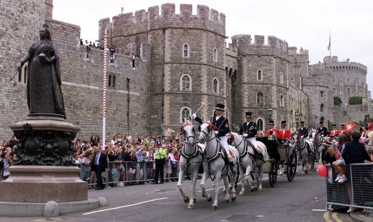 The carriage makes its way past the statue of Queen Victoria in front of Windsor Castle, U.K.