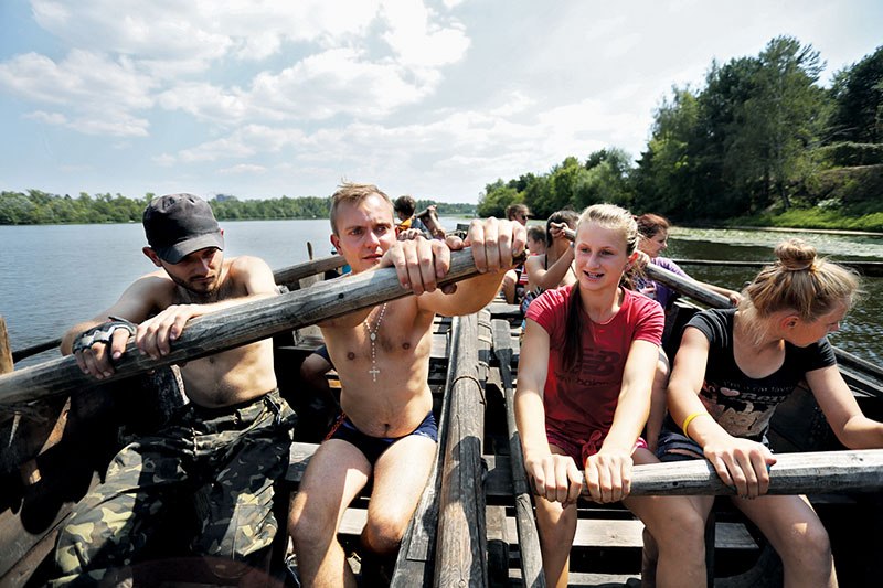 Children and staff from Trukhaniv Sich Cossack camp, located on Trukhaniv Island, row the oars of an ancient Cossack boat, called a baydak, on the Dnipro River on Aug 5.