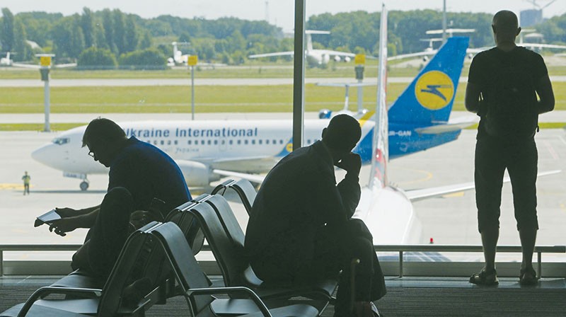 People sit at Kyiv Boryspil airport on May 30, 2013 with a view of an airplane operated by Ihor Kolomoisky’s Ukrainian International Airlines. (UNIAN)