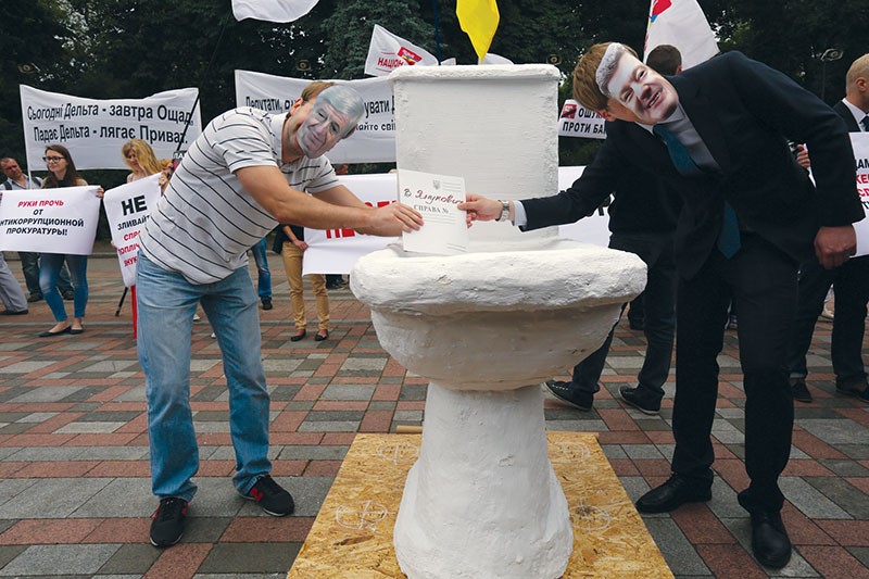 Activists wear masks depicting President Petro Poroshenko and then-Prosecutor General Viktor Shokin flushing criminal cases down a toilet bowl at a rally on June 17, 2015. Poroshenko and Shokin were accused of sabotaging corruption cases against ex-President Viktor Yanukovych and his allies. 