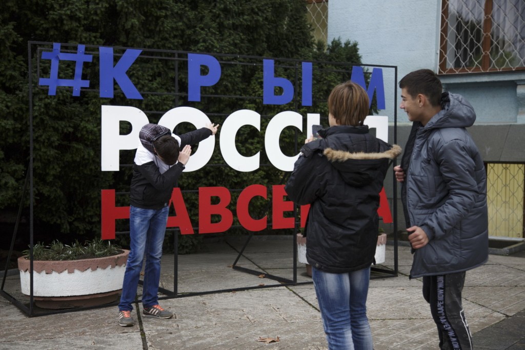 The song men take photos near the sign "Crimea - Russia - Forever" installed on Lenin square near the Council of Ministers of the Republic of Crimea on Oct. 14 in Simferopol.