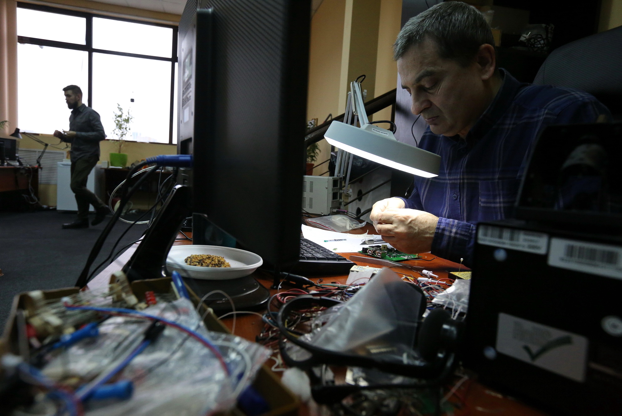 A man looks into a magnifier as he develops and assembles small parts of an Ajax security system at the company's Kyiv office on Nov. 10.