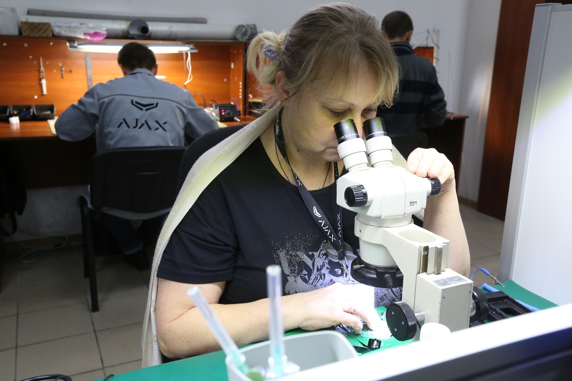 A woman employed by Ajax looks into the microscope.