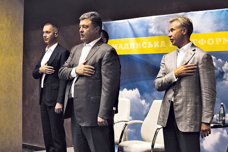 President Petro Poroshenko (C) with Borys Lozhkin, the president’s former chief of staff, and Yuriy Kosyuk (R) stand during the Ukrainian anthem at a meeting with members of Nova Kraina (New Country), a civil society group, on July 9, 2014. 