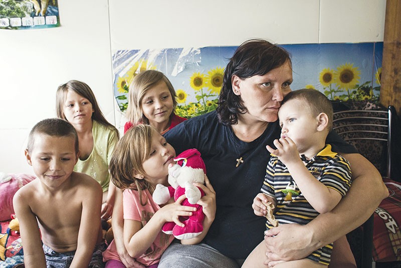 Olena Churina sits with five of her nine children inside their apartment in the Hope shelter in Kharkiv. 