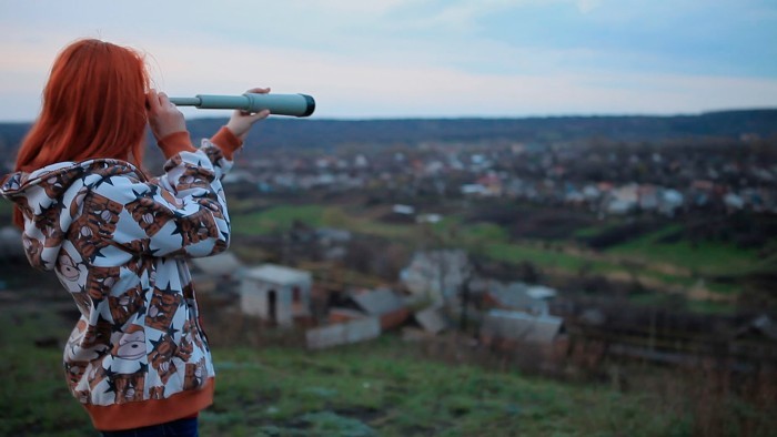 A girl looks through the binoculars at Mykolaivka city in "Shkola Number 3" documentary. (Courtesy) 