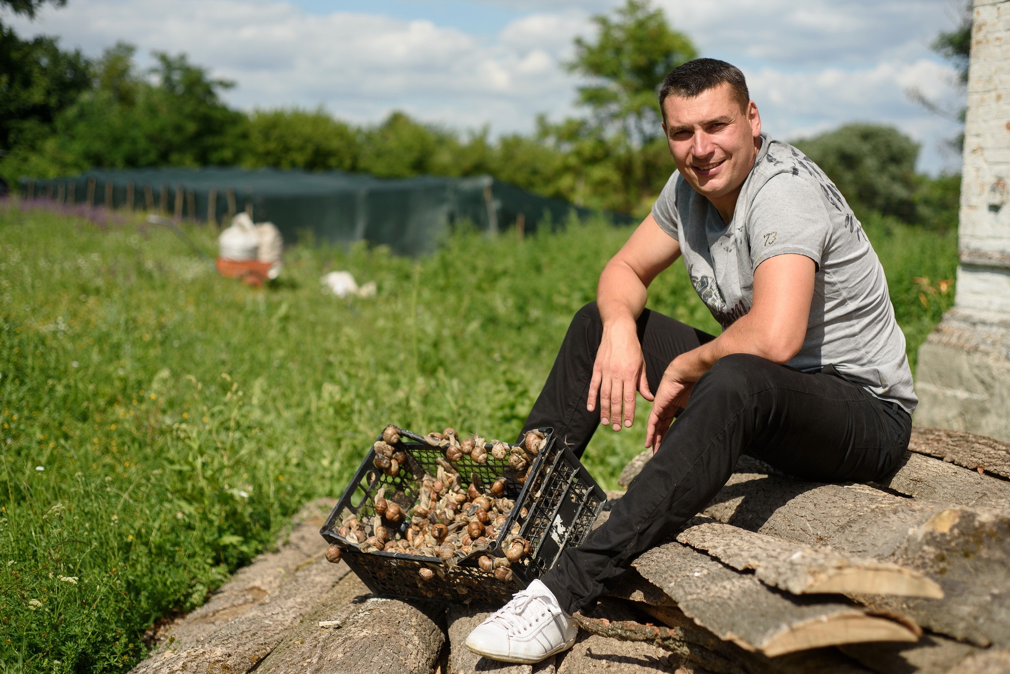Dmytro Butenko, founder of the Eco Ulitka farm, poses for a photo with his snails. ( Courtesy)