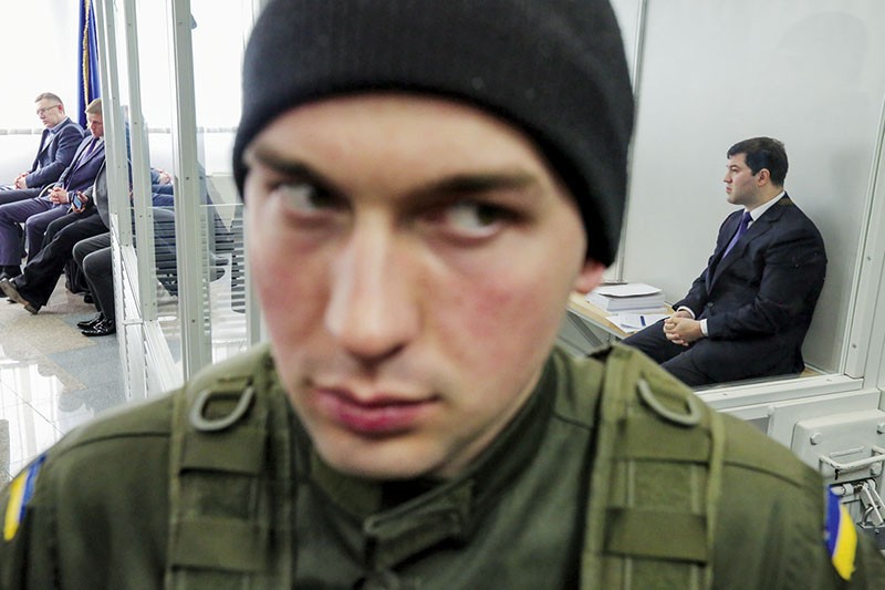 Roman Nasirov, chief of Ukraine’s State Fiscal Service, sits during a hearing at the Kyiv Court of Appeal on March 13 as a soldier stands guard in the foreground. 