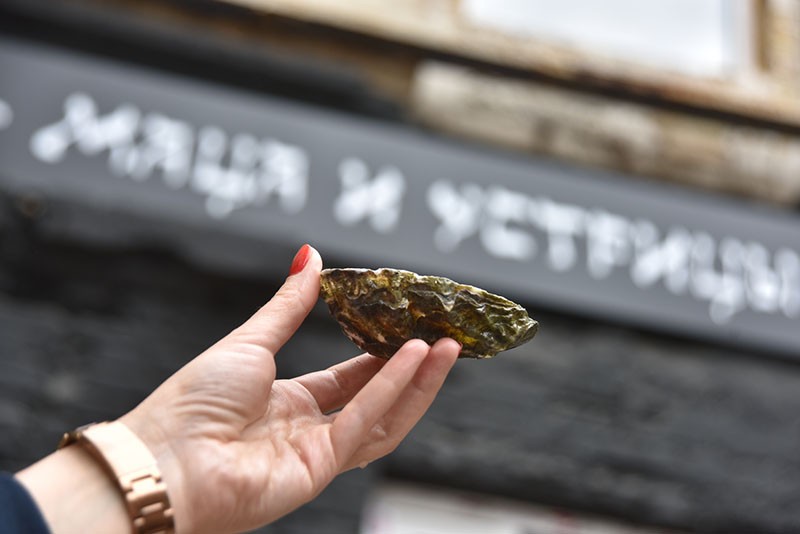 One of the employees of the Skifian Oysters holds an oyster near the entrance to Matza and Oysters bar in Kyiv on May 16. (Oleg Petrasiuk)