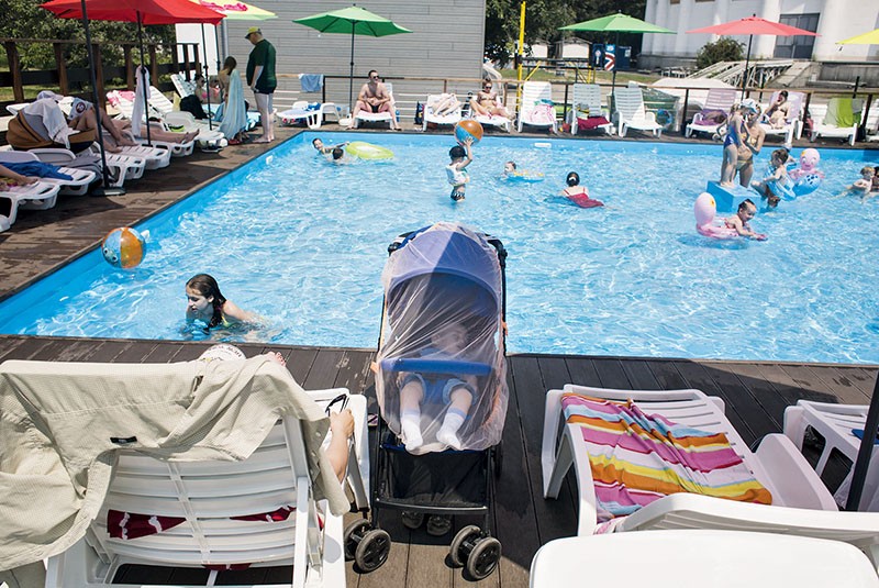 A child sleeps as people relax in the outdoor pool at VDNH expocenter on June 27.