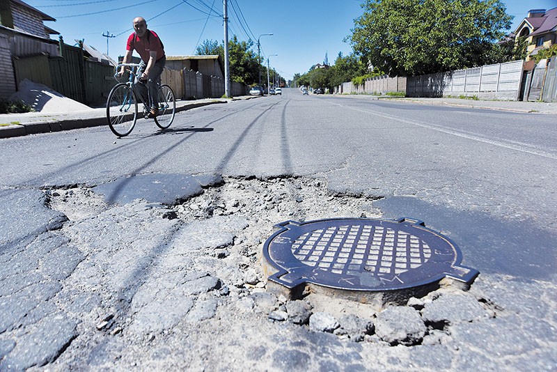 A man rides a bicycle on a bumpy road in Kyiv Oblast on June 3. (Oleg Petrasiuk)