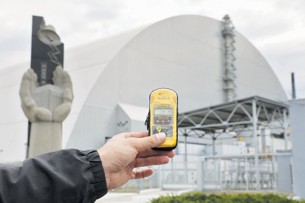 A man holds a Geiger counter near the New Safe Confinement covering the destroyed reactor No. 4 at the Chornobyl nuclear plant on July 9. 