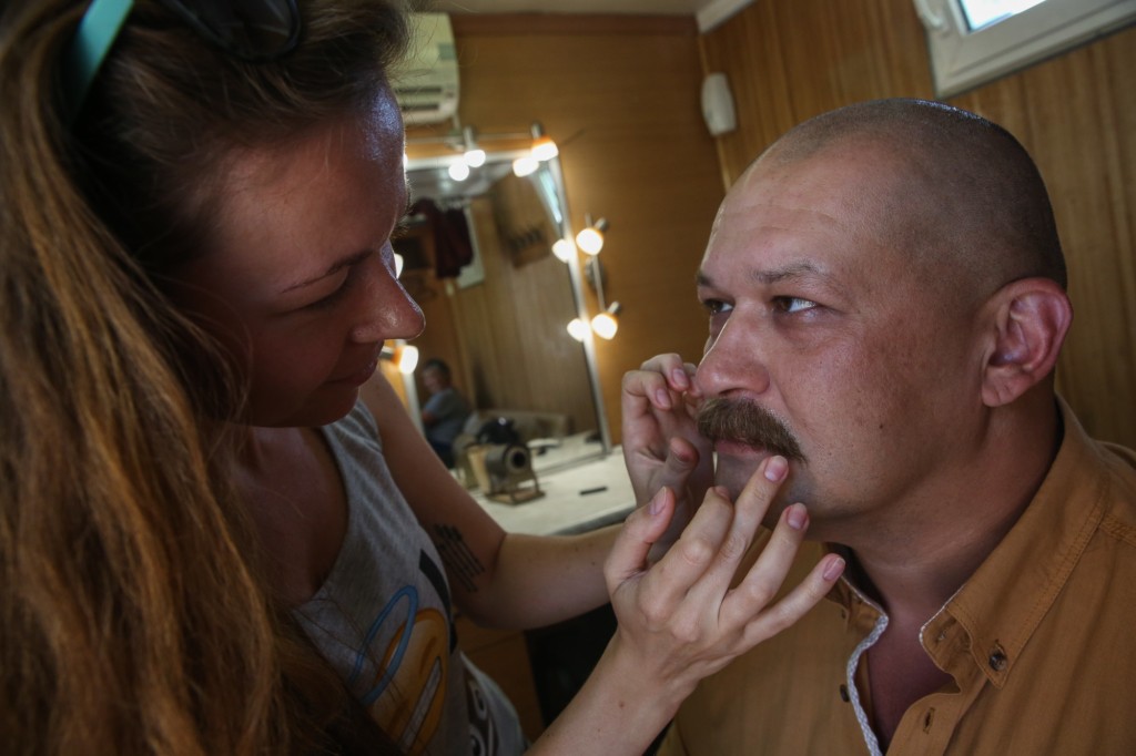 An actor Georgiy Povolotskiy gets his mustache attached as he prepares to the scene during the shooting of "Voroshylovgrad" movie near Starobilsk, Luhansk Oblast, on Aug. 18. 