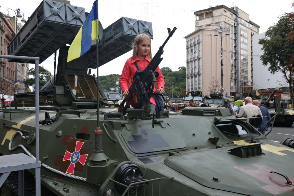 A girl stands at a machine gun slot attached to a Strela anti-aircraft missile unit during the arms fair in Kyiv on August 22.