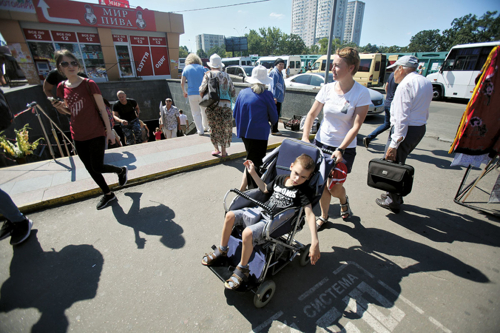 Viktoria Panasyuk and her 10-year-old son Yehor who uses a wheelchair walk in Kyiv on Aug. 8. (Kostyantyn Chernichkin)
