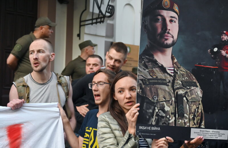 Activists hold a picture depicting Ukrainian serviceman Vitaly Markiv as they shout 